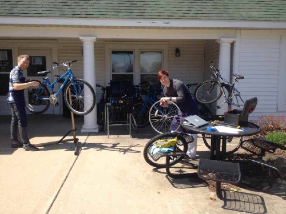 2 students fixing bikes on the patio